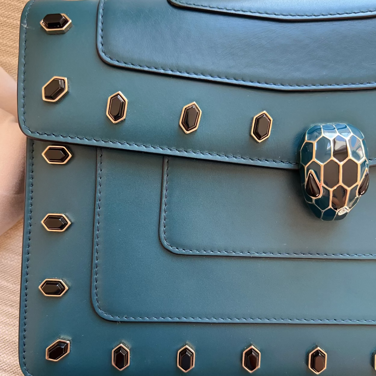 Blue handbag with snake head clasp on a wooden surface