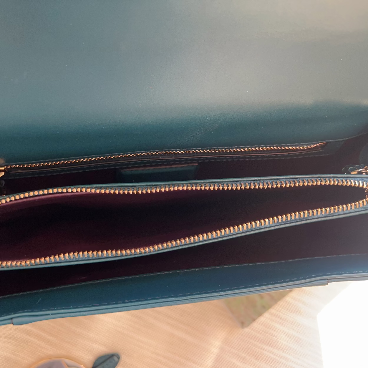 Close-up of a blue handbag with gold zipper on a wooden surface