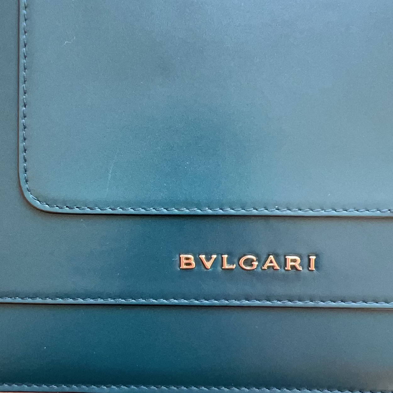 Teal Bvlgari handbag on a wooden surface