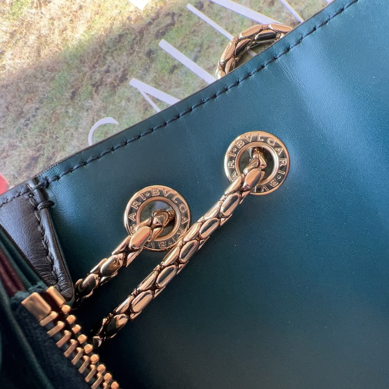 Close-up of a green leather clutch with decorative gold chain and tassel