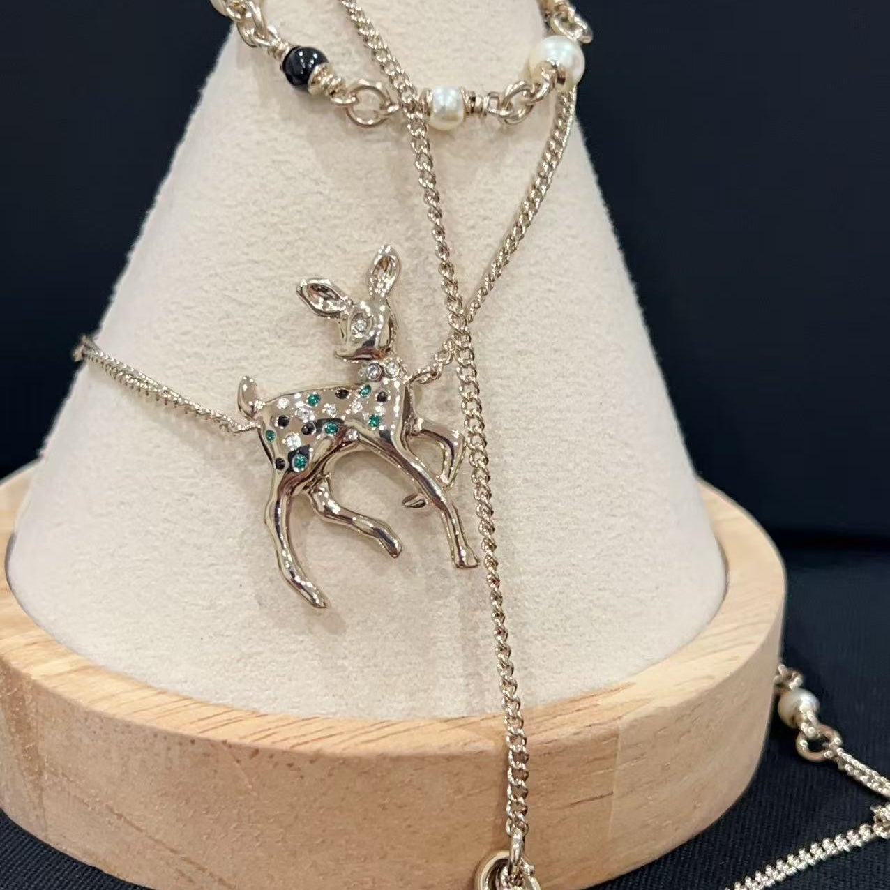 Necklace with a deer pendant on a wooden stand against a dark background