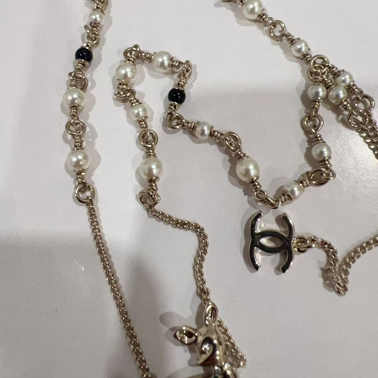 Chanel necklace with pearl and chain details on a white background