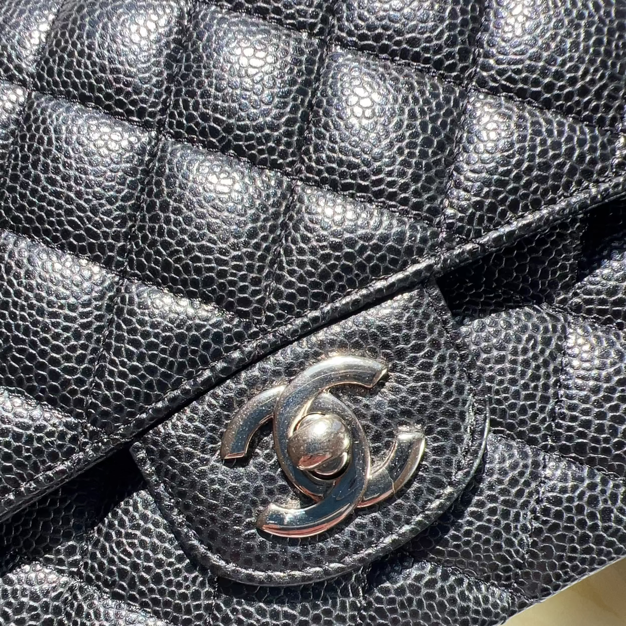 Close-up of a black quilted handbag with Chanel logo.