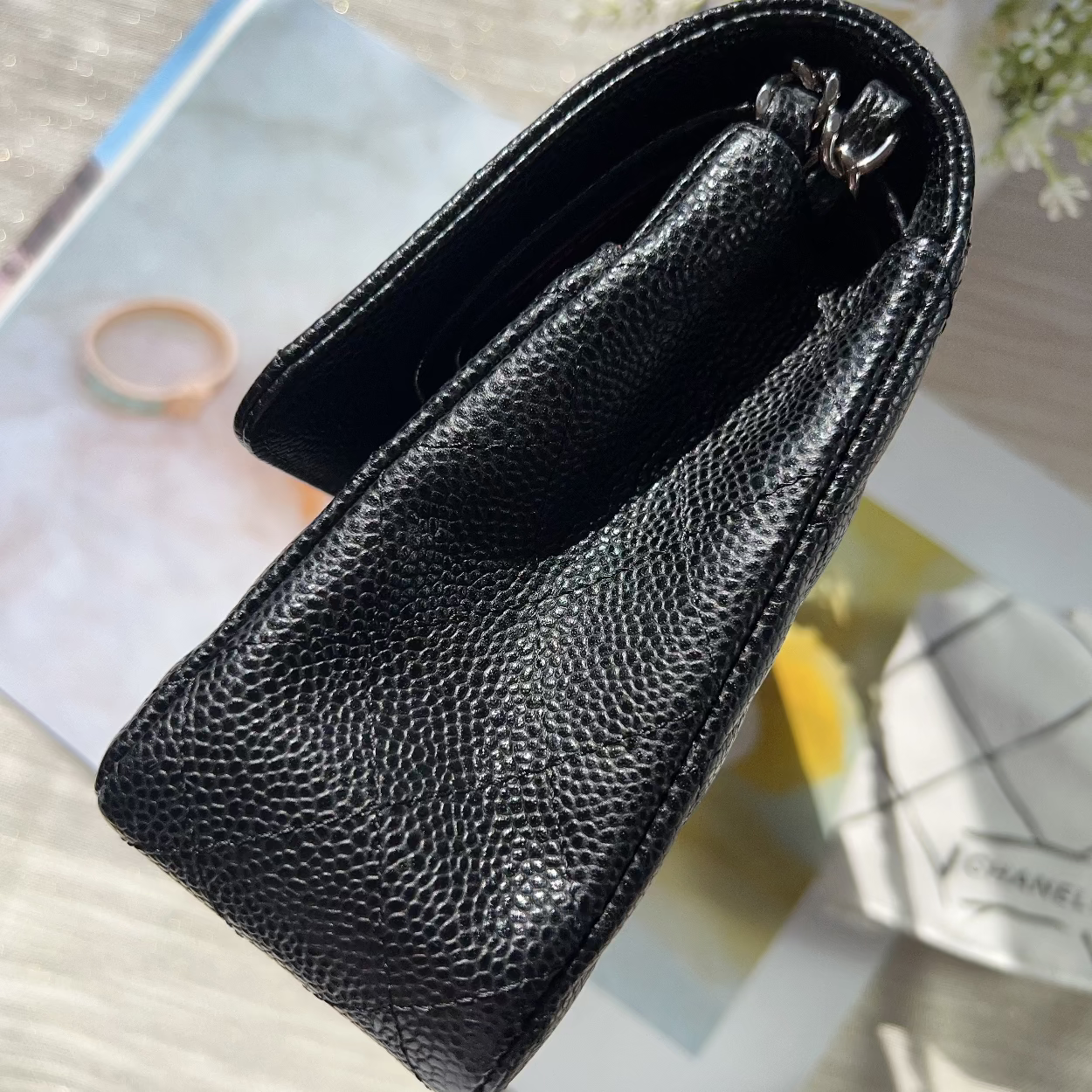 Black textured wallet on a magazine with flowers in the background