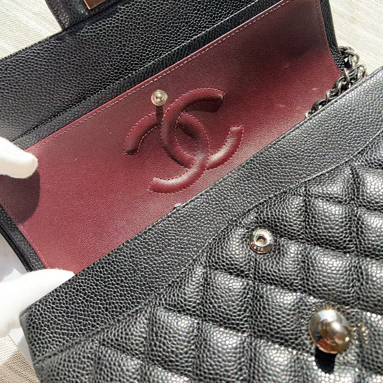 Close-up of a black quilted handbag with a red interior and gold hardware.
