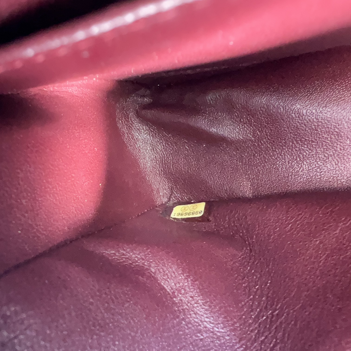 Close-up of a maroon leather surface with a small yellow label.