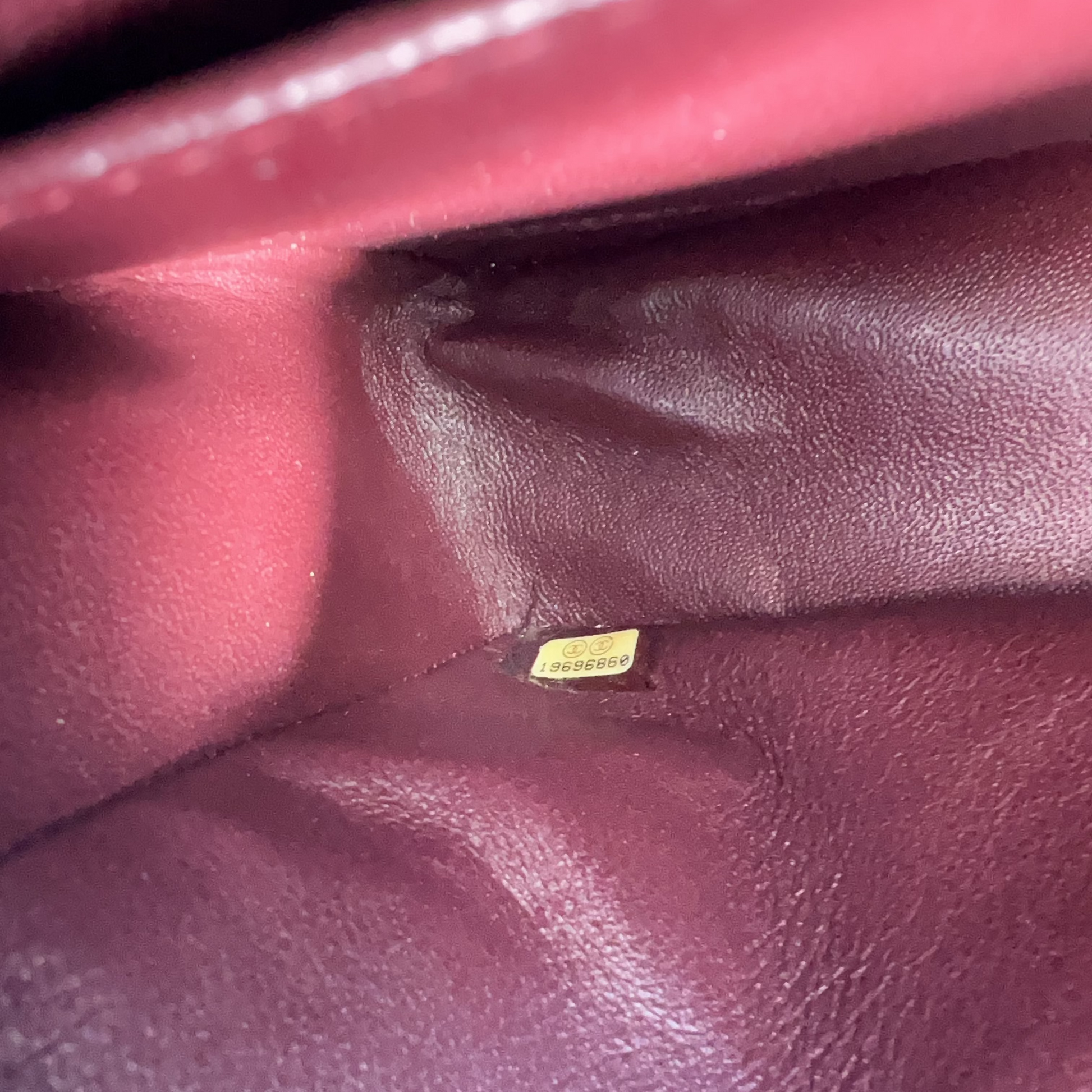 Close-up of a maroon leather surface with a small yellow label.