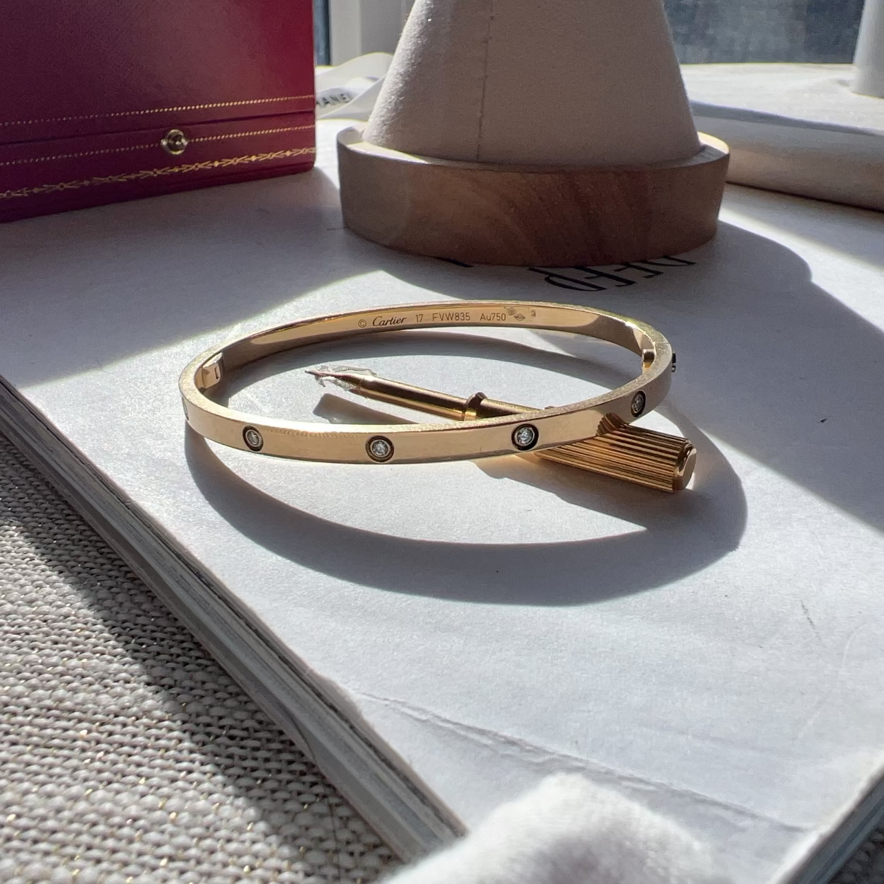 Gold bracelet on a surface with a book and other items in the background