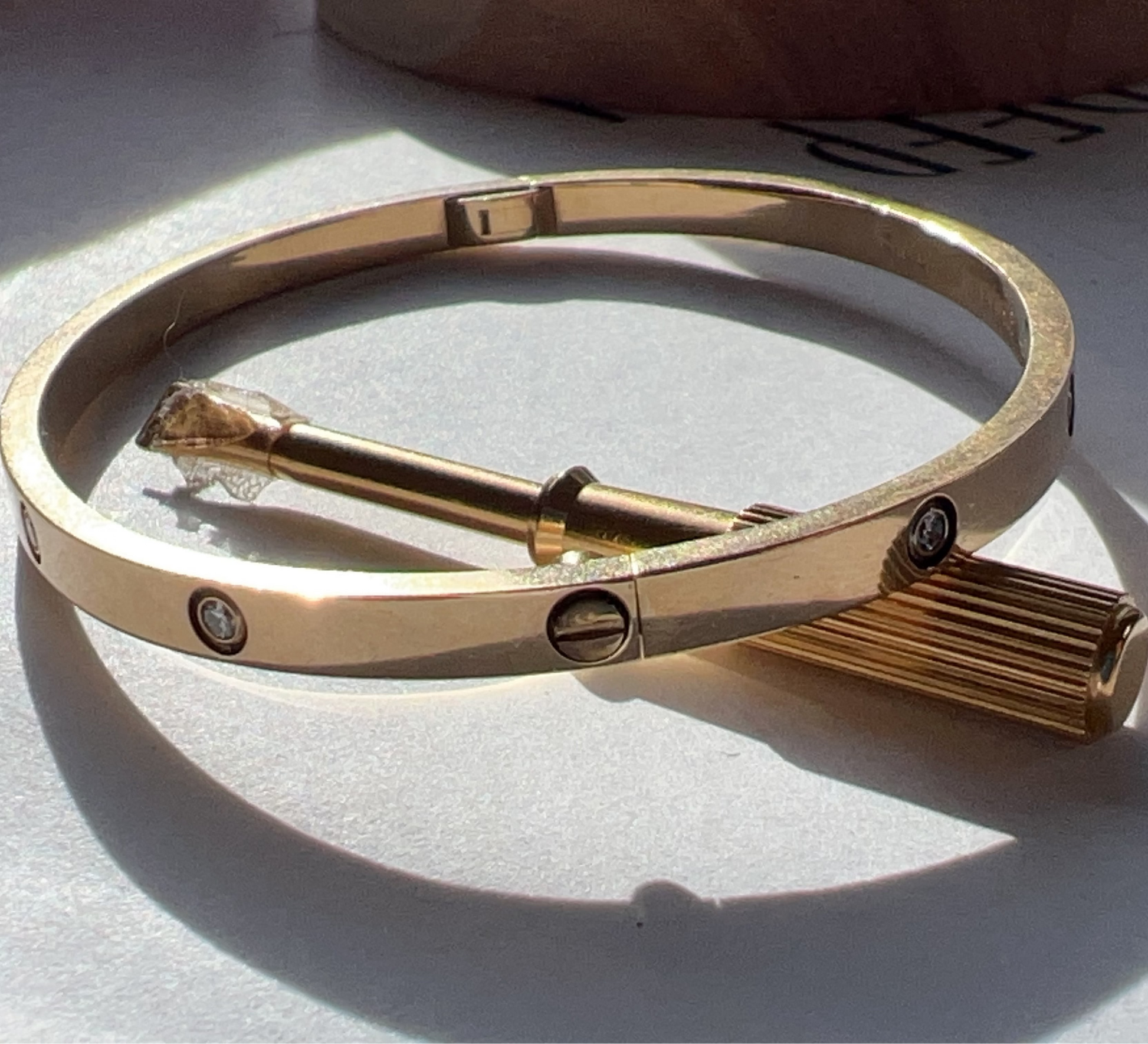 Gold bracelet on a light surface with shadows