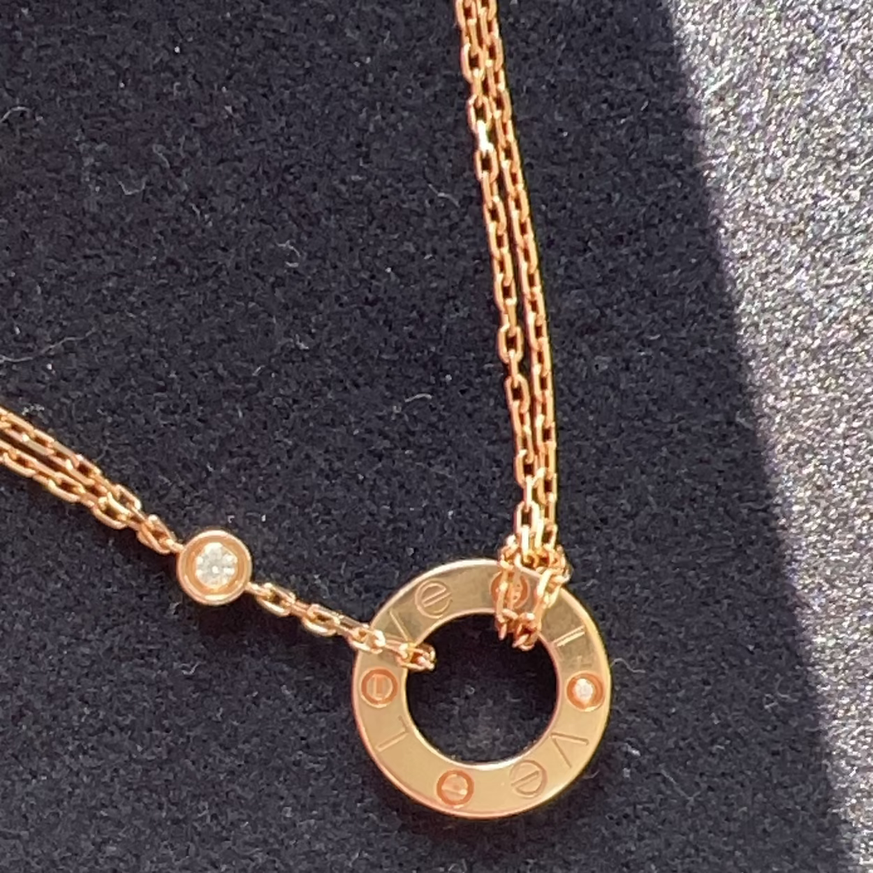 Rose gold necklace with a circular pendant on a dark background