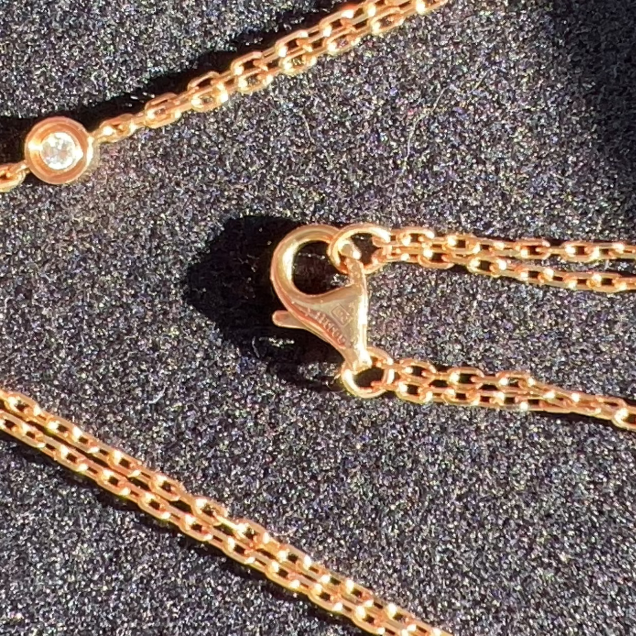 Close-up of a gold chain with a clasp on a dark background