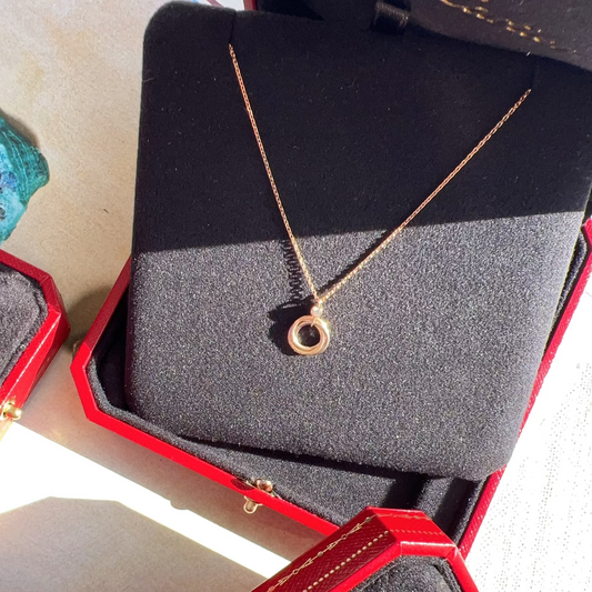 Gold necklace in a red jewelry box on a light background