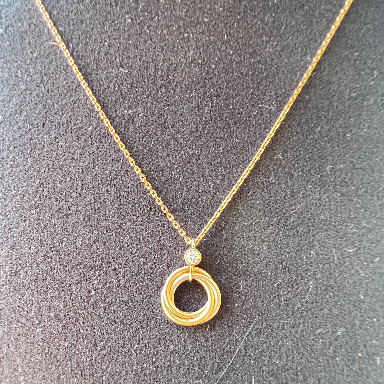 Gold necklace with a circular pendant on a textured gray surface