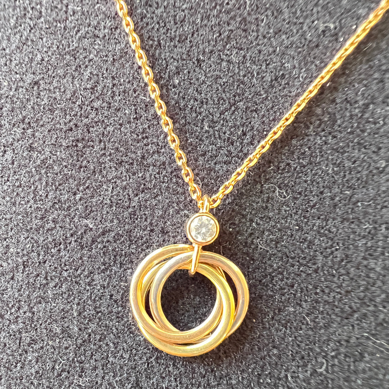 Gold necklace with circular pendant on a gray surface