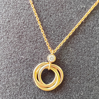 Gold necklace with circular pendant on a gray surface
