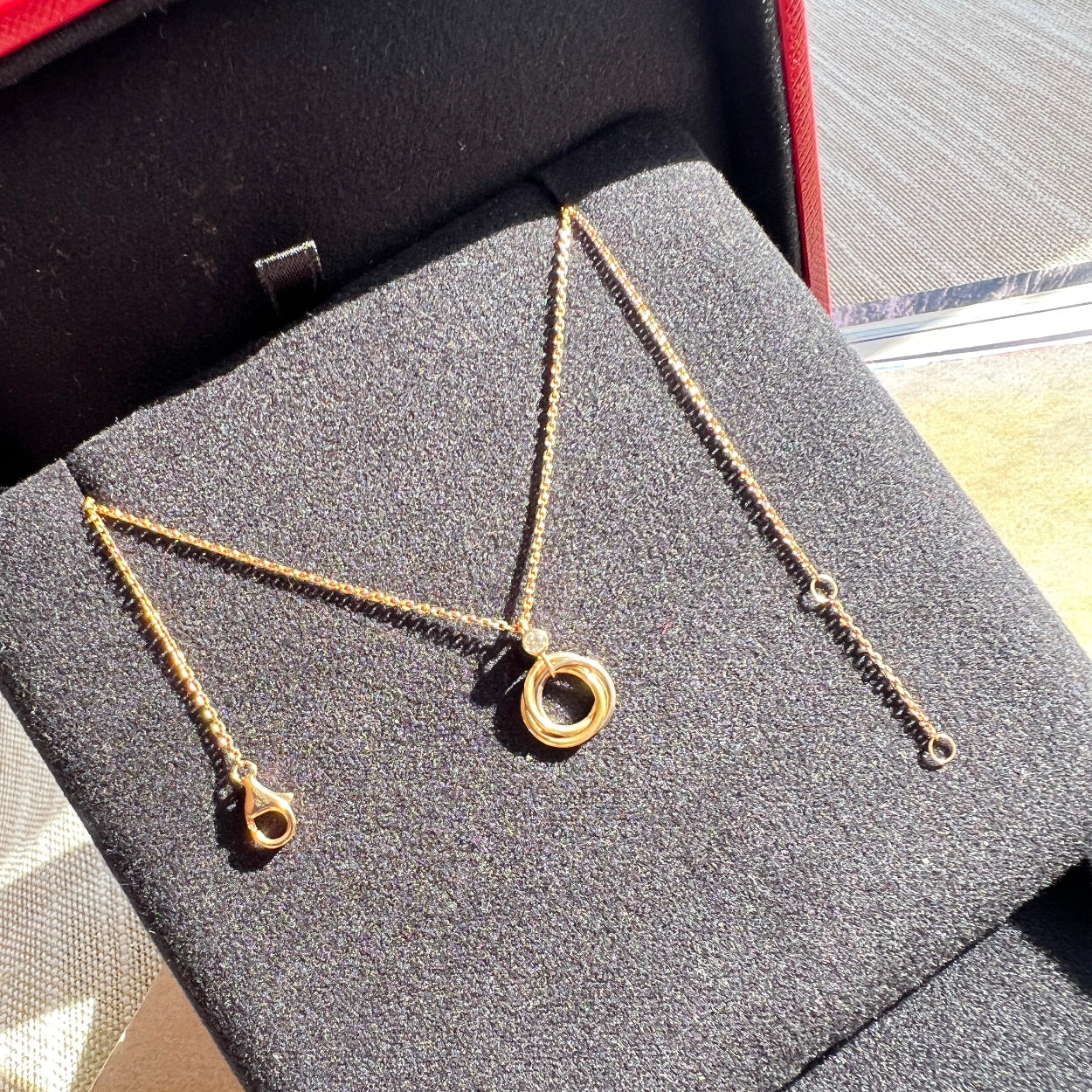 Gold necklace on a gray textured surface with a red border