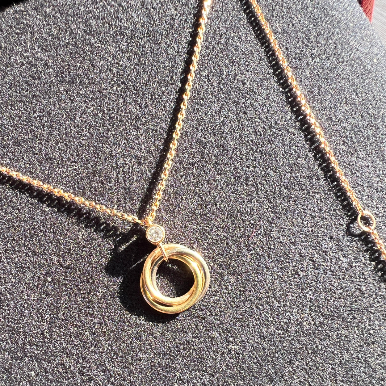 Gold necklace with a circular pendant on a textured gray surface