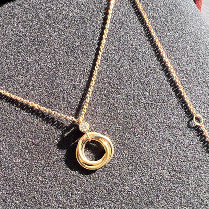 Gold necklace with a circular pendant on a textured gray surface