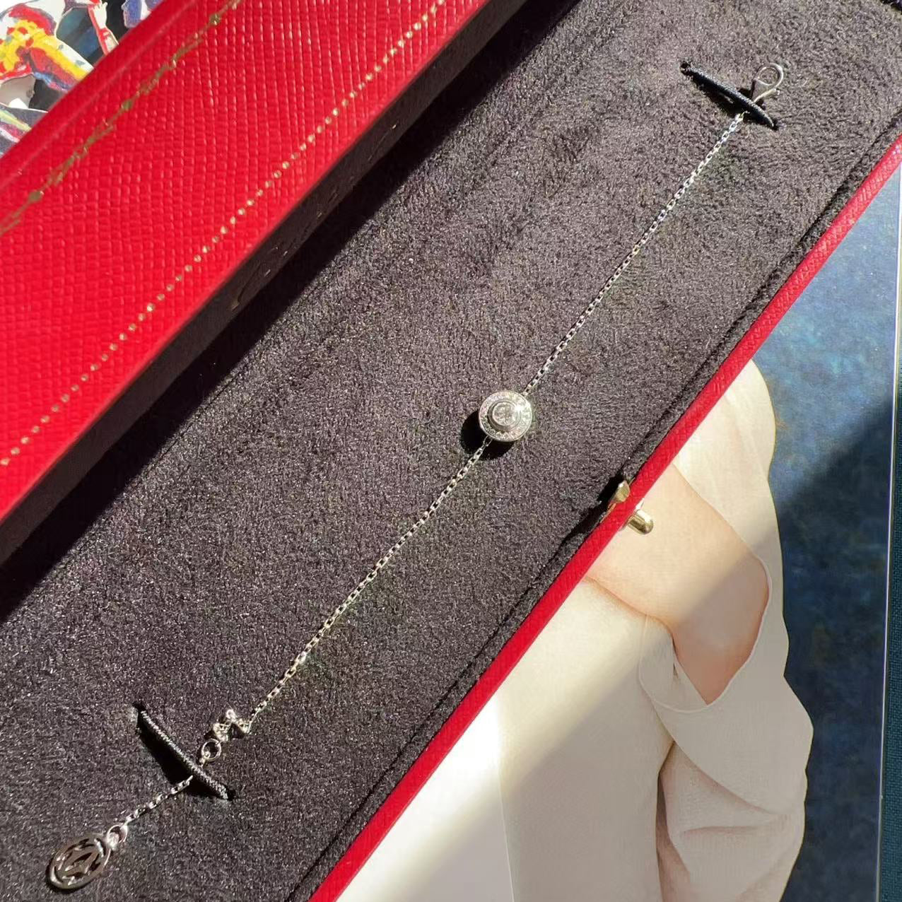 Silver necklace with a pendant on a gray surface with a red border