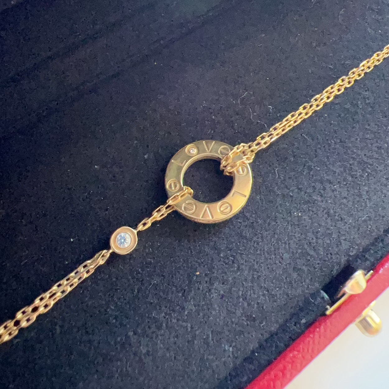 Gold necklace with a circular design on a dark surface, featuring the Cartier brand.