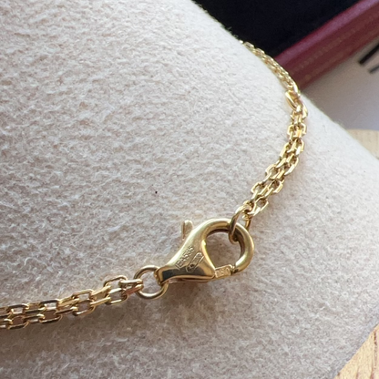 Close-up of a gold bracelet with clasp on a textured surface