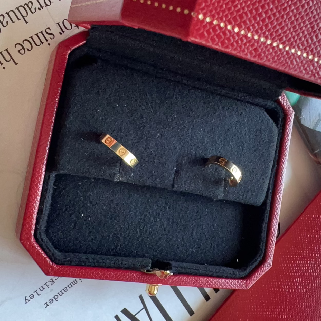 Gold ring in a red and black jewelry box with a handwritten note.