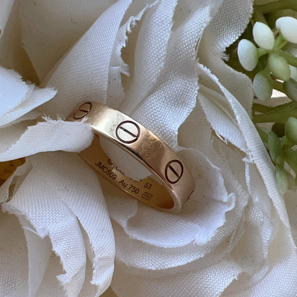 Gold ring with symbols on a white flower