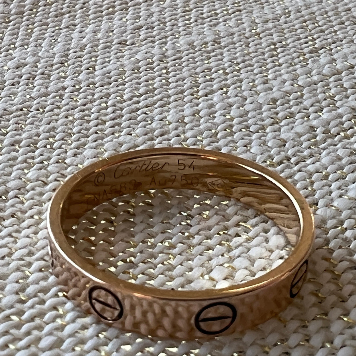 Gold ring with engraved symbols on a textured white surface