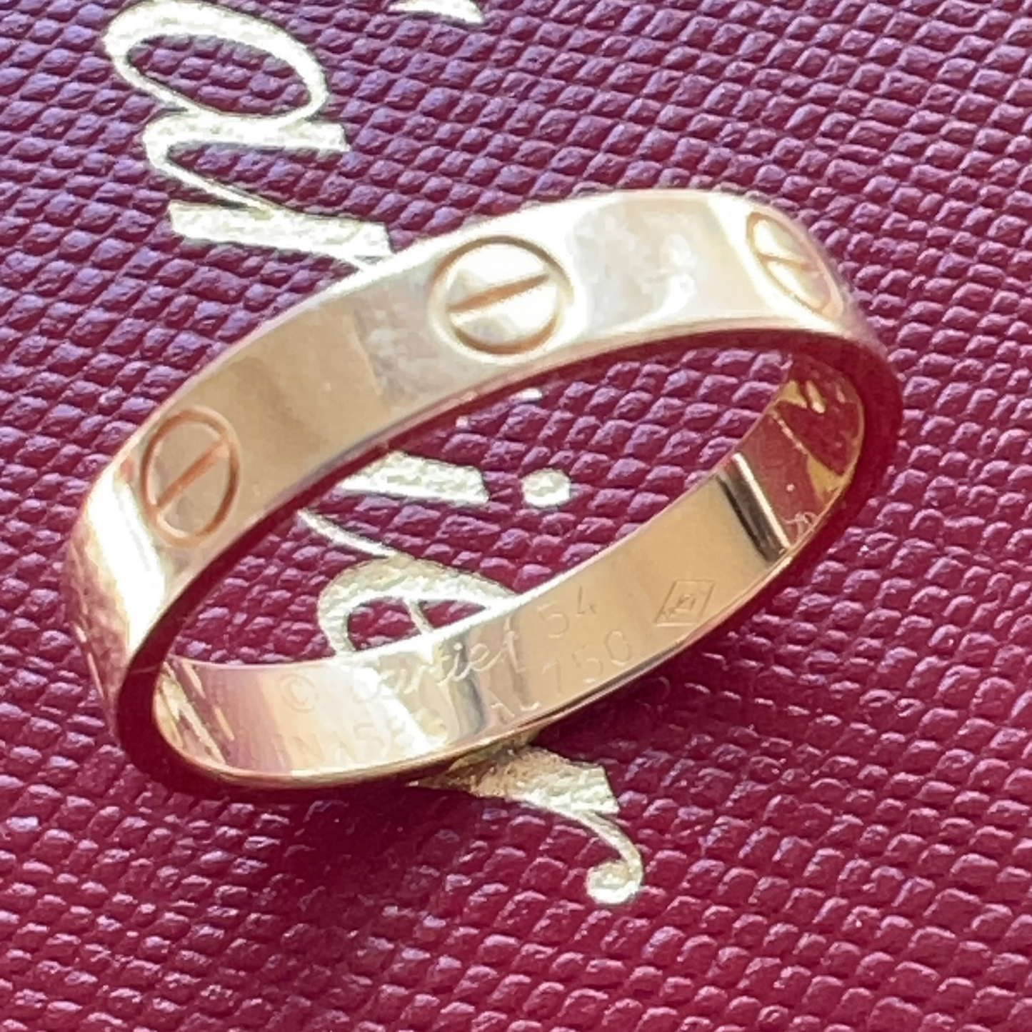 Gold ring with screw designs on a red textured background