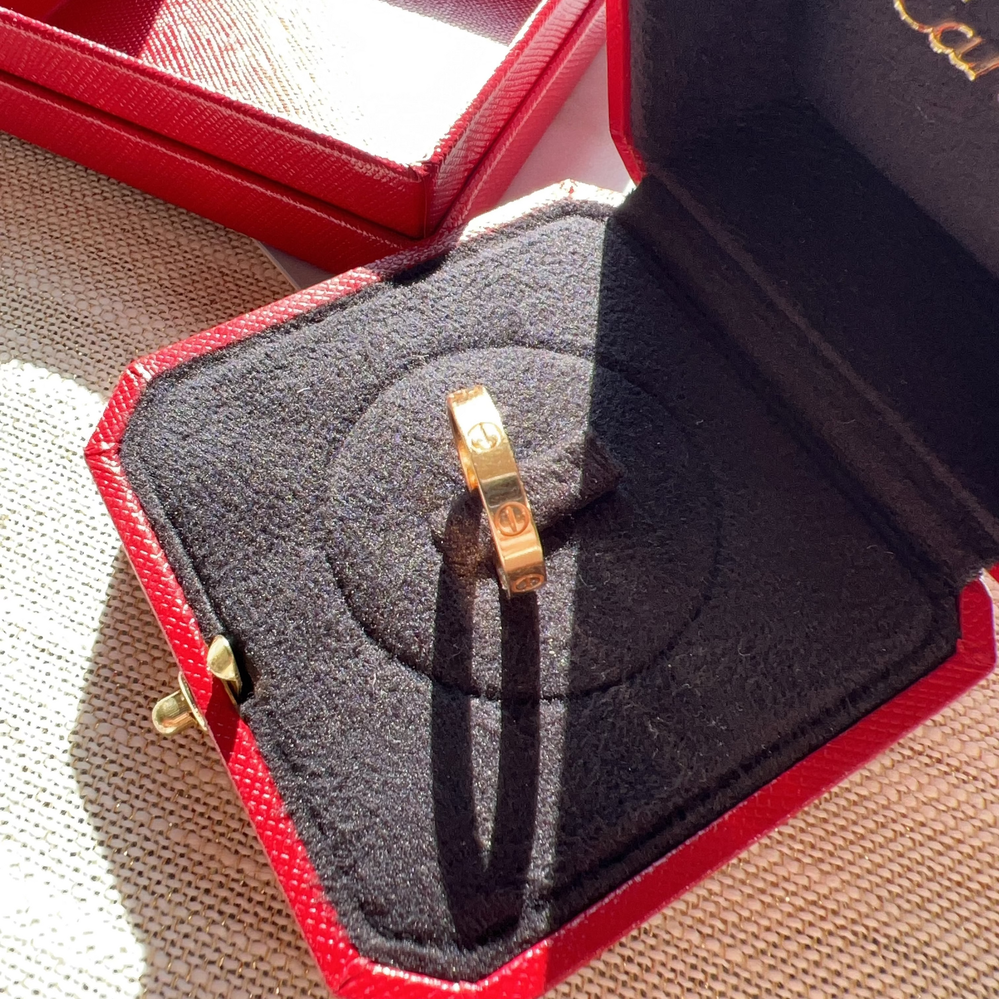 Gold ring in a Cartier box on a textured surface