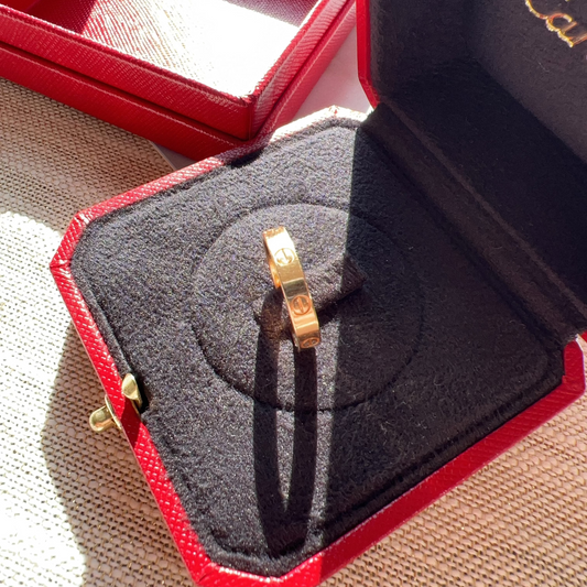 Gold ring in a Cartier box on a textured surface