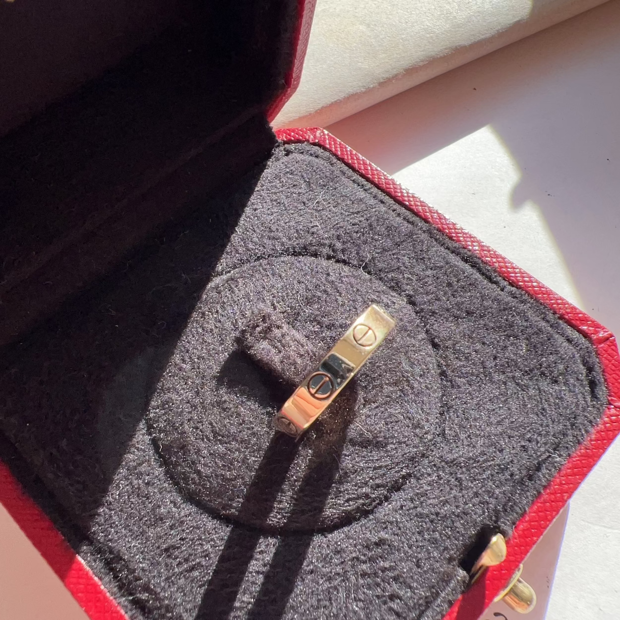 Gold ring in a jewelry box with 'Cartier' branding.