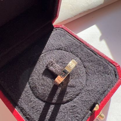 Gold ring in a jewelry box with 'Cartier' branding.