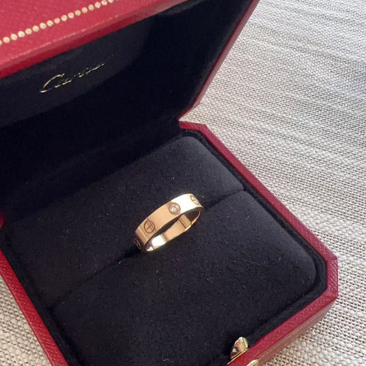 Rose gold ring in a red jewelry box with visible brand name.