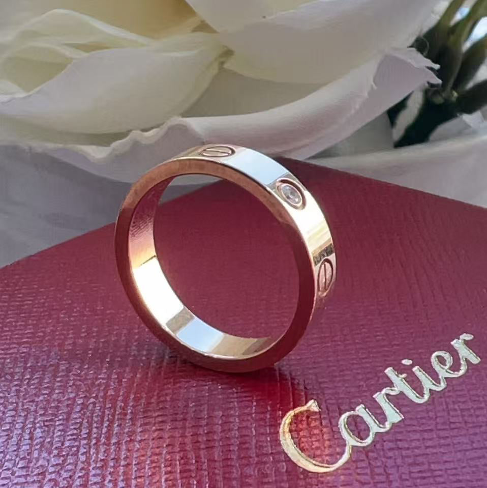 Gold Cartier ring on a red box with white flowers in the background