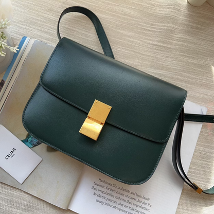 Green handbag with gold clasp on a table with books and flowers