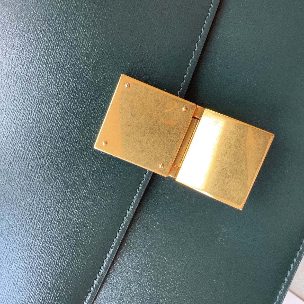 Gold clasp on a green leather bag