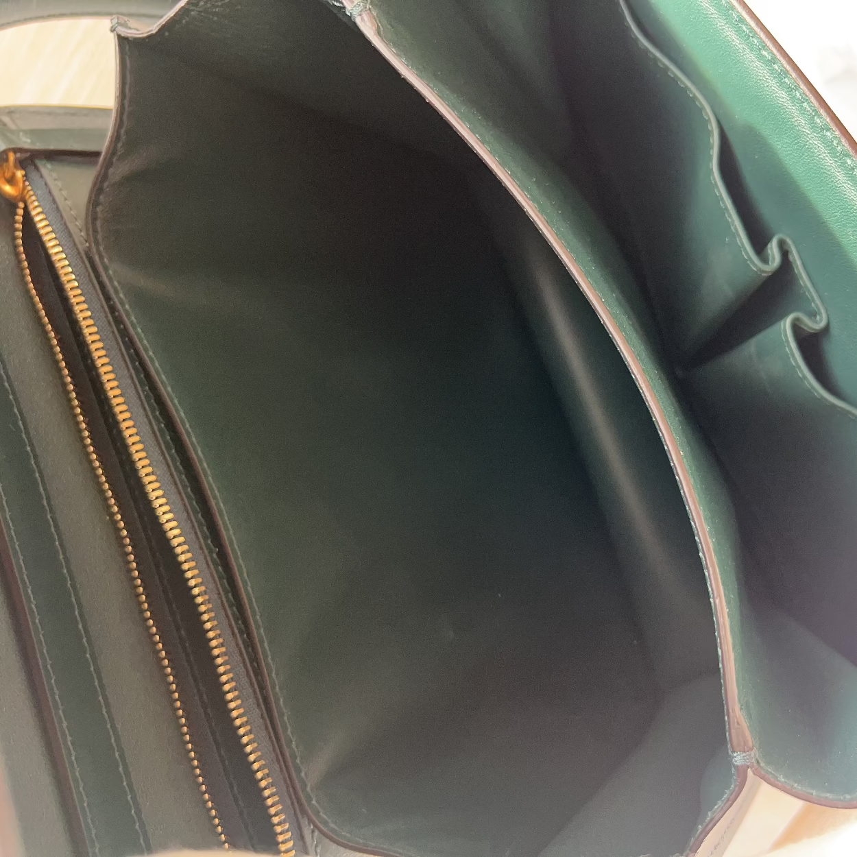 Close-up of a green leather bag with gold zipper detail.