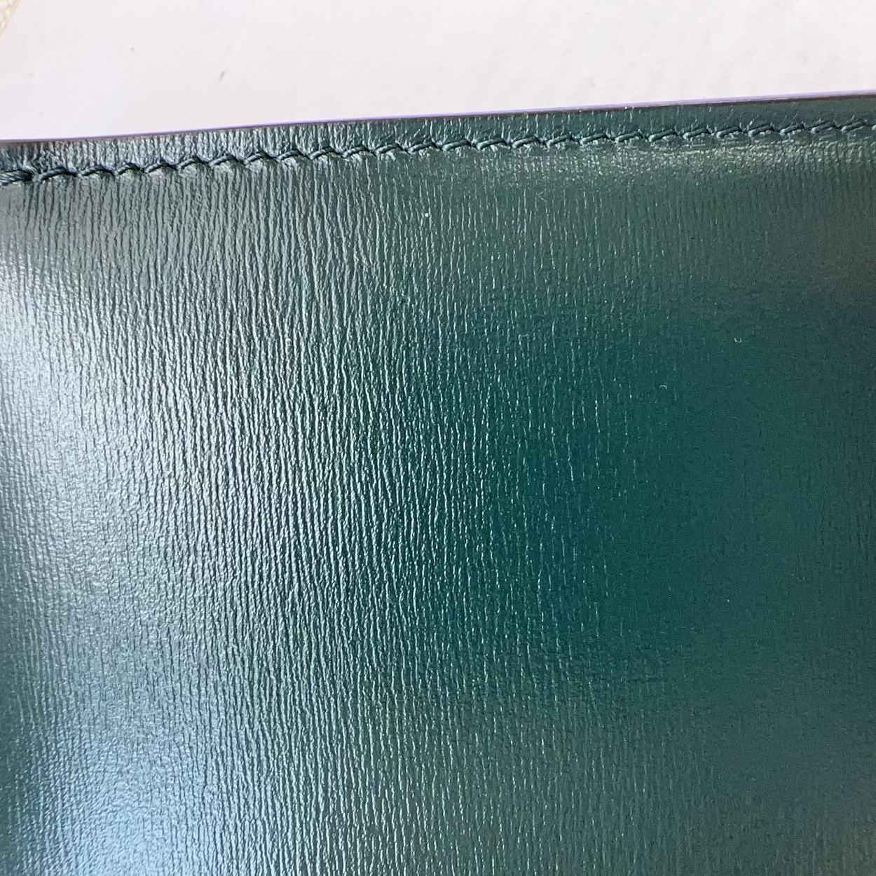 Close-up of a green leather wallet with visible stitching on a white background