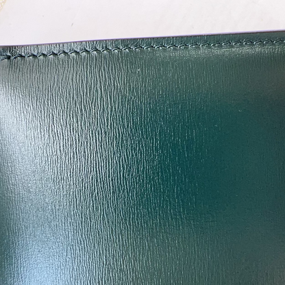 Close-up of a green leather wallet with visible stitching on a white background