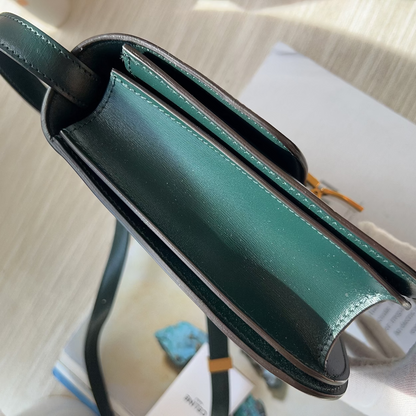 Green leather clutch bag on a light fabric surface