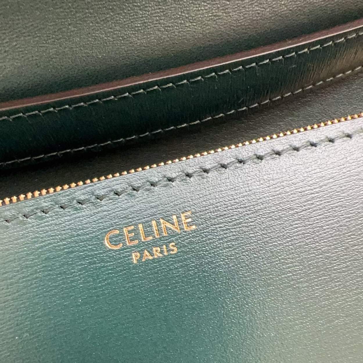 Close-up of a green leather product with 'Celine Paris' logo.