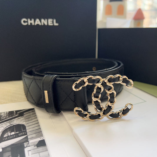 Black quilted leather belt with gold CC logo on a surface, with 'Chanel' branding in the background.
