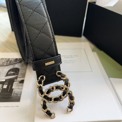 Black quilted leather belt with gold chain detail on a magazine