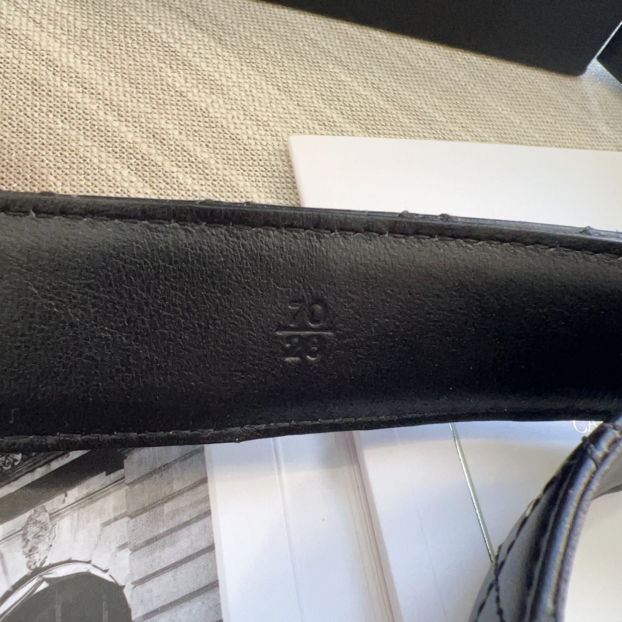 Close-up of a black leather strap with a brand logo on a textured surface.
