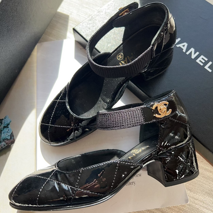 Black patent leather shoes with Chanel logo on a branded box