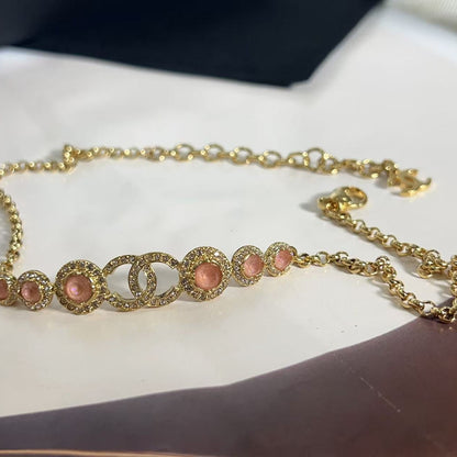 Gold bracelet with pink stones on a white surface