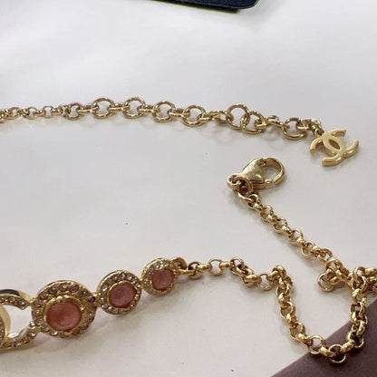 Gold chain with pink stones on a white surface