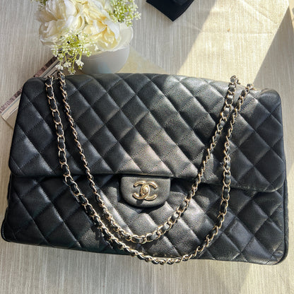Black quilted handbag with chain strap on a wooden surface with flowers and a black box.