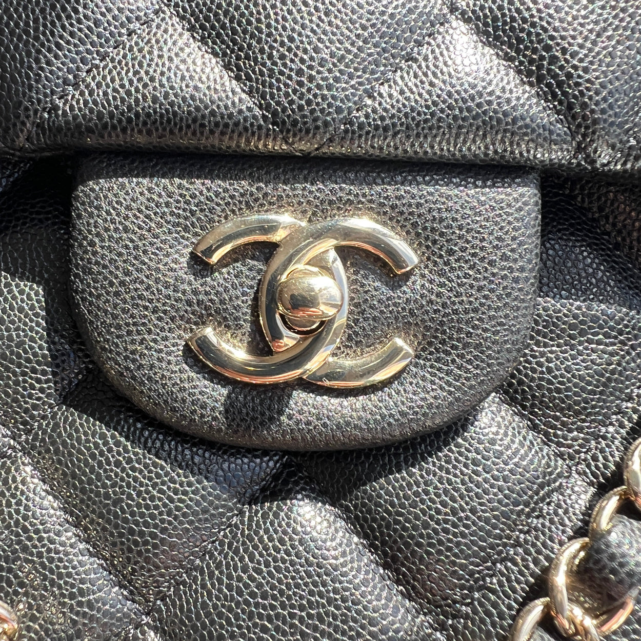 Close-up of a black quilted handbag with a silver Chanel logo.